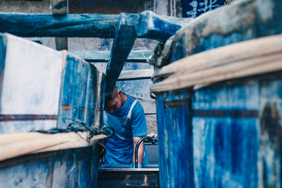 A dyer working beside indigo vats in a workshop