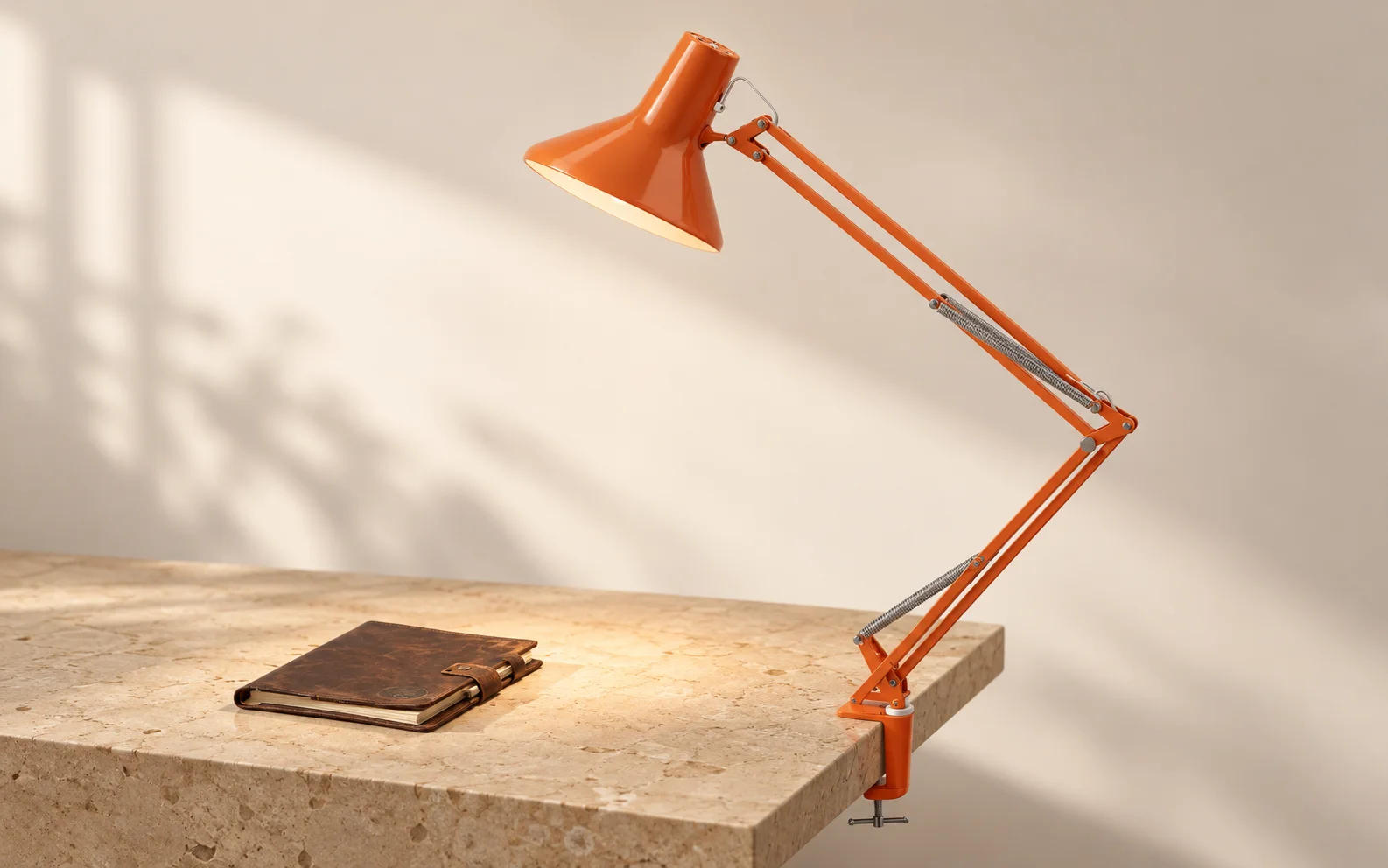 AI-enhanced studio image of an orange articulated lamp and notebook on a sunlit stone desktop