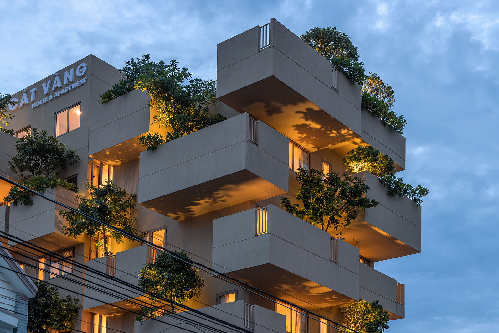 Staggered planted balconies and warm lighting at Cat Vang Hotel & Apartment, from TAA DESIGN