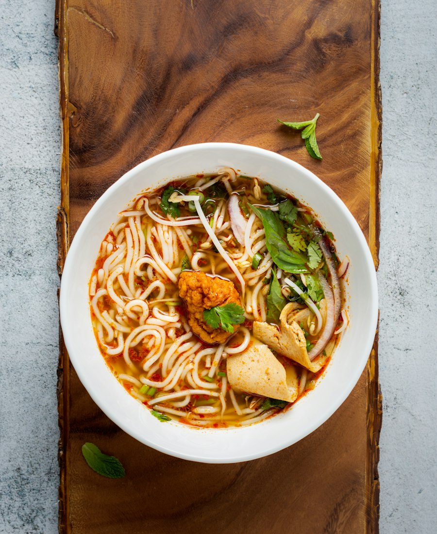 Bowl of spicy noodle soup with chilli oil and herbs